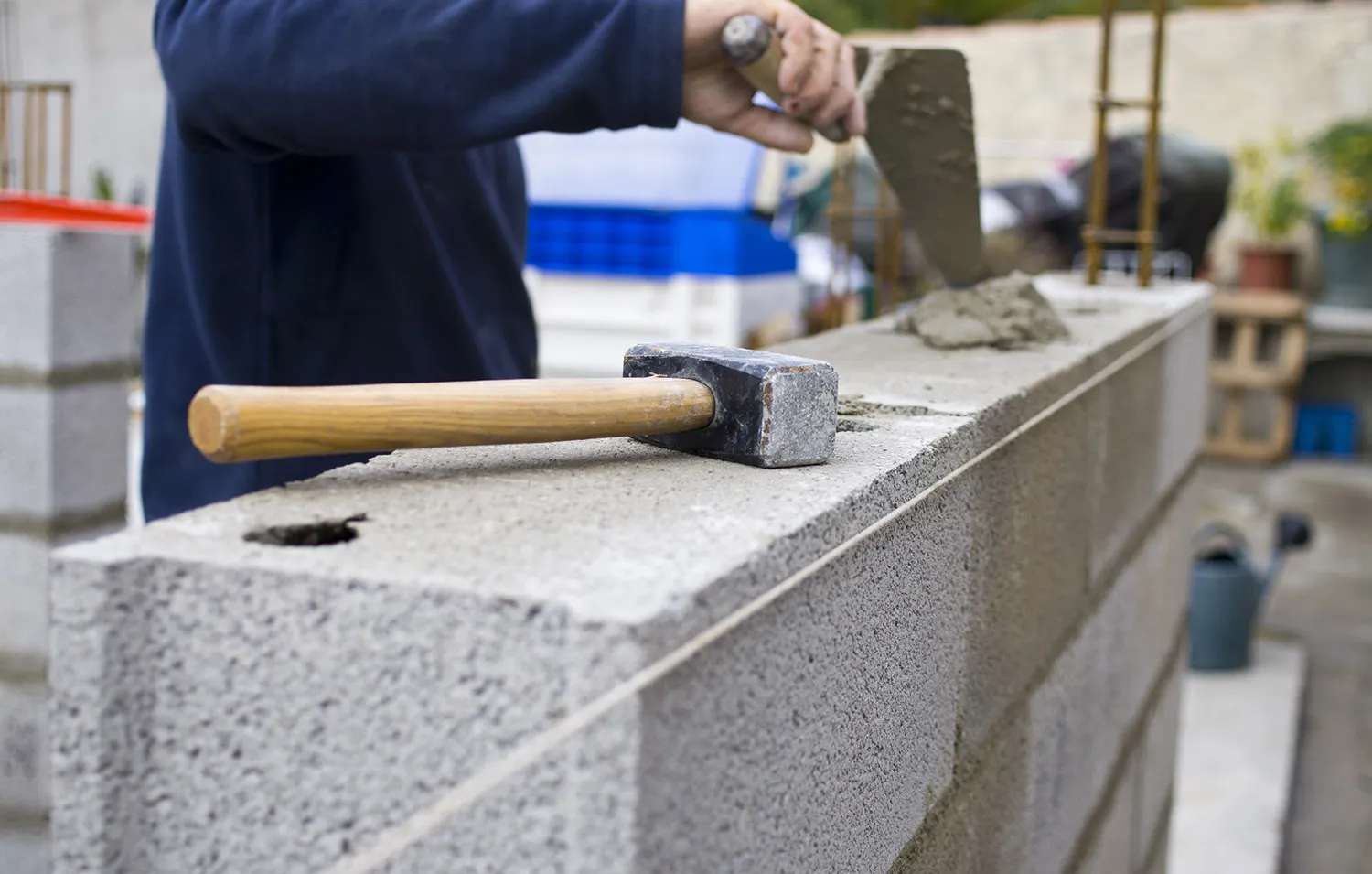 Un maçon applique du mortier sur un mur en blocs de béton avec une truelle